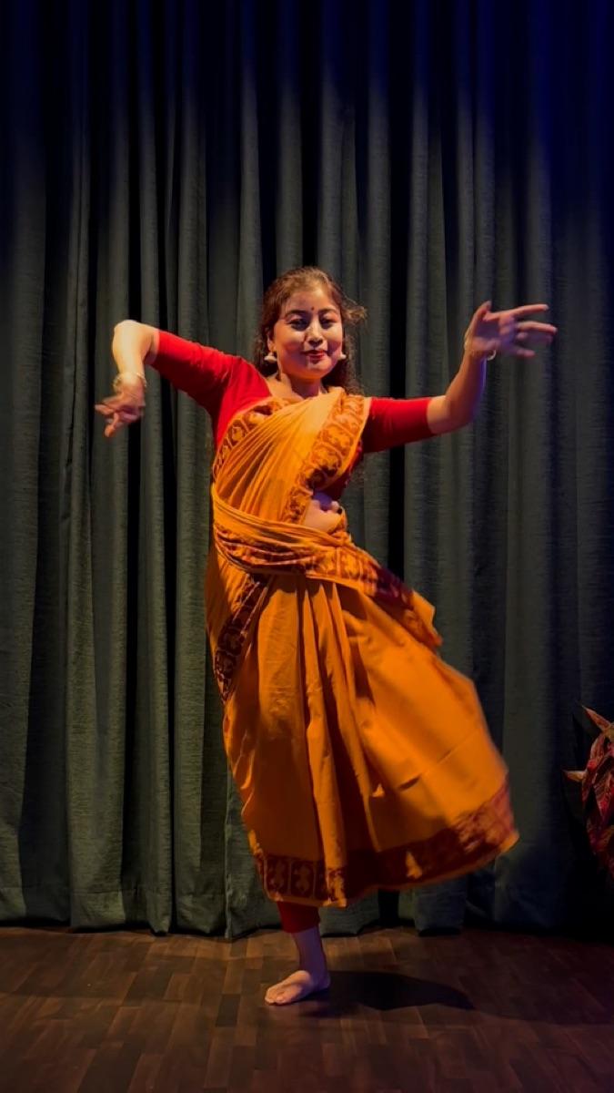 Dancer in an orange saree performing a semi-classical dance
