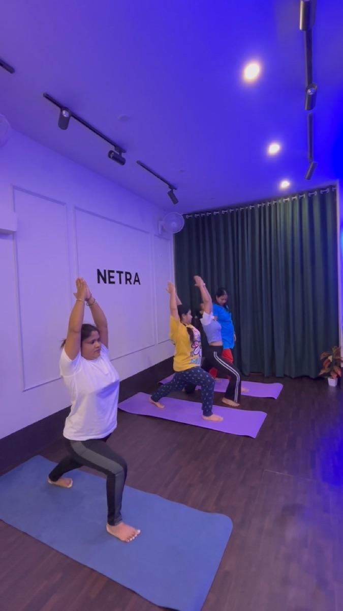 Yoga students holding a warrior pose on their mats
