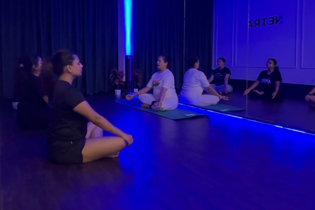 Students sitting cross-legged in a calm, guided breathing practice at Netra
