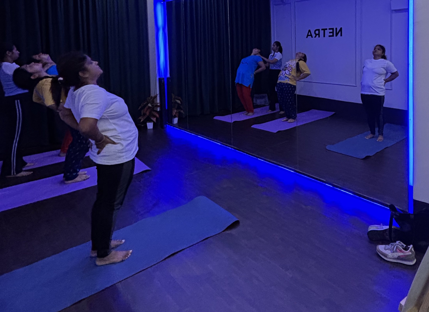 Student easing into a gentle standing backbend on her mat at Netra