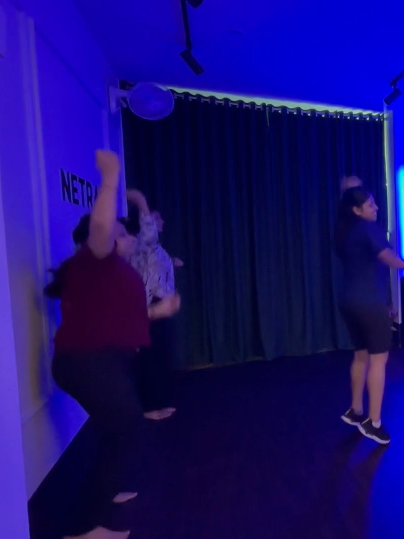 Zumba students raising their arms high during a routine, seen from the side